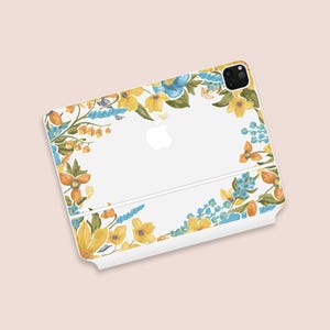 May include: White iPad case with a floral pattern. The case has yellow, blue, and orange flowers with green leaves. The flowers are arranged around the edges, forming a decorative border.