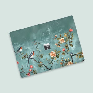 Pode incluir: Uma capa para laptop turquesa com um design floral que apresenta flores rosa e amarelas, folhas verdes e pássaros azuis. O design lembra a arte chinesa tradicional.