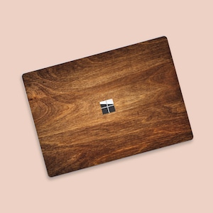 Puede incluir: Una piel de portátil de madera marrón con un logotipo de Windows blanco y negro.