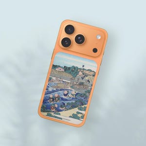 Puede incluir: Funda de teléfono inteligente naranja con una impresión de arte japonés. La funda tiene un diseño rectangular con una escena de paisaje colorida. La funda tiene tres lentes de cámara y un flash.