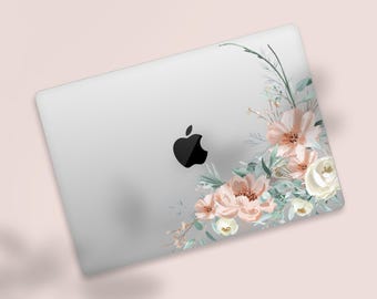 May include: A silver laptop with a black Apple logo, adorned with a floral design. The design features peach-colored flowers, white roses, and green foliage, creating a soft, elegant aesthetic. The laptop is set against a light pink background.