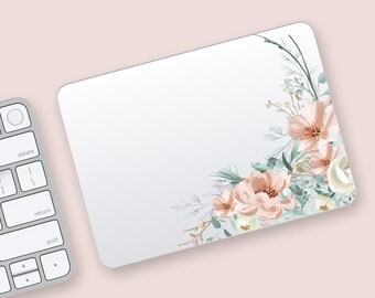 May include: A white rectangular mousepad with rounded corners. The mousepad features a floral design in the upper right corner, with peach and white flowers, and green leaves. A silver keyboard is in the lower left corner.