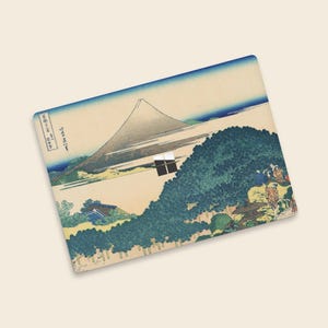 May include: Rectangular mousepad featuring a Japanese landscape print. The artwork depicts Mount Fuji, a large tree, and figures in traditional clothing. The color palette includes blues, greens, and beige, with Japanese text in the upper left corner.