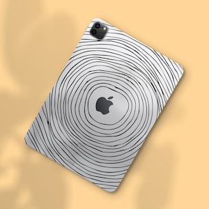 Może przedstawiać: Biały iPad Pro z czarno-białym wzorem koncentrycznych okręgów. Logo Apple jest widoczne na środku. Tablet posiada podwójny obiektyw aparatu w lewym górnym rogu.