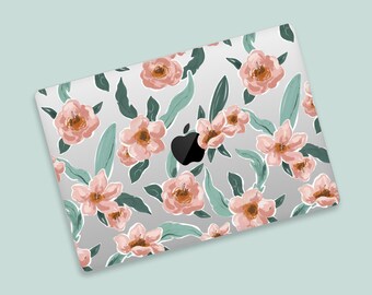 May include: A laptop with a floral design. The cover features a pattern of peach-colored flowers and green leaves on a gray background. The Apple logo is visible in black. The laptop is angled on a light blue surface.