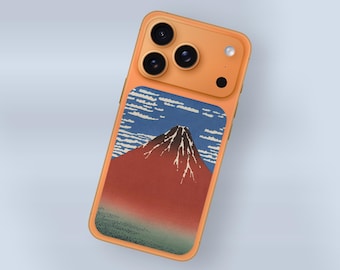 May include: Orange phone case featuring a Japanese-style mountain landscape design. The case has a triple-lens camera and a small black dot. The mountain is red with white accents, set against a blue sky with white clouds.