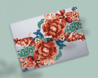 May include: A laptop with a floral design. The design features large, red-orange flowers with green leaves and blue accents. The laptop is light gray and sits on a light green surface.