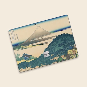 May include: A laptop skin featuring a Japanese landscape with Mount Fuji, trees, and a river. The skin has a vintage aesthetic with a color palette of blue, beige, and green. The Microsoft logo is visible on the bottom right.
