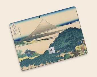 May include: A laptop skin featuring a Japanese landscape with Mount Fuji, trees, and a river. The skin has a vintage aesthetic with a color palette of blue, beige, and green. The Microsoft logo is visible on the bottom right.