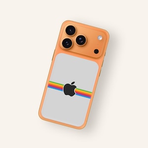 Puede incluir: Funda de teléfono naranja con parte trasera gris con el logotipo negro de Apple y una franja arcoíris. La funda tiene tres lentes de cámara y un flash. La funda del teléfono es de diseño retro.