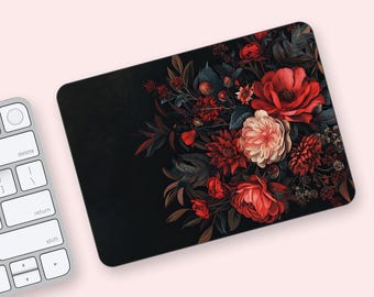 May include: Black rectangular mousepad featuring a floral design. The design includes red, pink, and cream-colored flowers with dark green leaves. The mousepad is on a light pink surface, with a white keyboard in the corner.