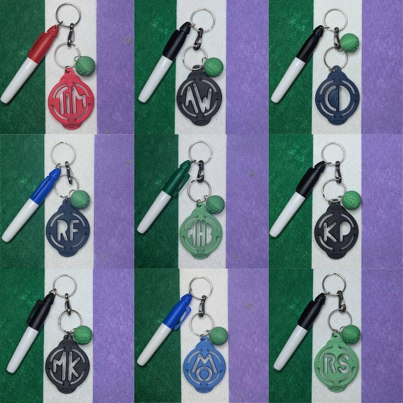 May include: Nine keychains with a black and white dry erase marker attached to each. Each keychain has a green, blue, or red circle with a white monogram in the center. The circles are attached to a silver key ring.