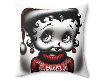 Op de afbeelding: Een wit kussen met een zwart-witte illustratie van een cartoonfiguur dat een rode trui draagt met de tekst "Merry Christmas".