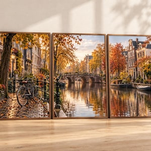 May include: A triptych wall art set featuring a scenic canal view in autumn. The images display cobblestone paths, a parked bicycle, arched stone bridges, historic buildings, and calm water reflecting vibrant orange and yellow fall foliage.