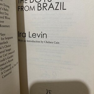 May include: A white book cover with black text that reads "The Boys From Brazil" by Ira Levin. The book cover also includes the text "With an Introduction by Chelsea Cain" and a small black and white image of a sailboat with the word "Corsair" underneath.