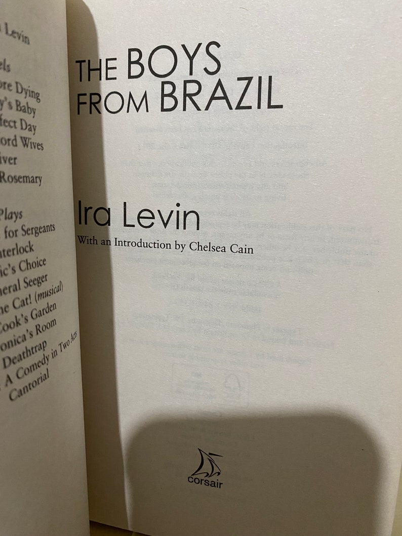 May include: A white book cover with black text that reads "The Boys From Brazil" by Ira Levin. The book cover also includes the text "With an Introduction by Chelsea Cain" and a small black and white image of a sailboat with the word "Corsair" underneath.