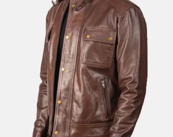 May include: Brown leather jacket with a stand-up collar, two chest pockets, and a front zipper. The jacket has gold-colored buttons and a ribbed knit collar. The sleeves have buttoned cuffs. The jacket is worn over a black shirt.