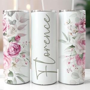 May include: Three stainless steel tumblers with a floral design. The tumblers are white with pink and white flowers and green leaves. The middle tumbler has the name "Florence" written in cursive on the front.