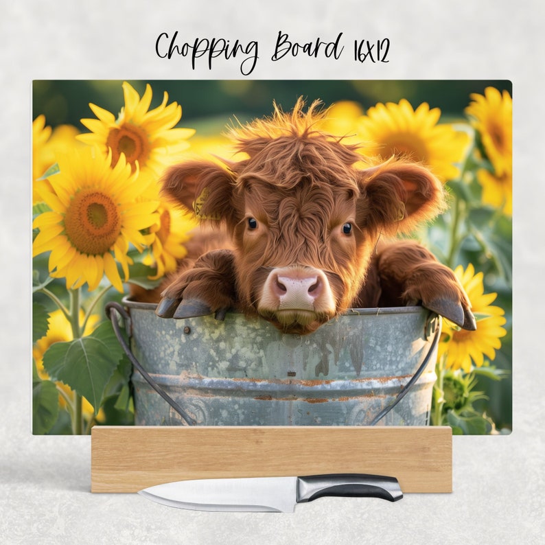 May include: A brown and white Highland calf sits in a metal bucket surrounded by yellow sunflowers. The calf is looking directly at the camera. The text "Chopping Board 16x12" is written in black at the top of the image.