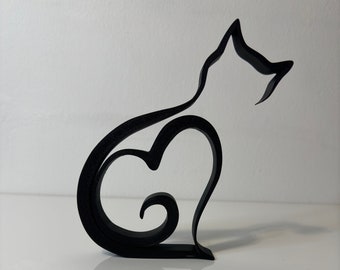 Puede incluir: Silueta negra de un gato con una forma de corazón en su cuerpo. El gato está sentado sobre una superficie blanca.