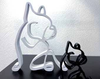 May include: Two stylized sculptures of French Bulldogs, one white and one black, are posed sitting on a black surface. The sculptures are made of a smooth, solid material.