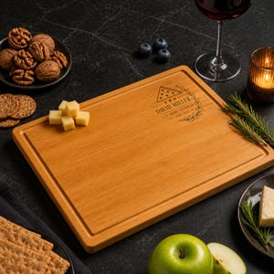 May include: A rectangular wooden cutting board with a juice groove, engraved with a folded flag icon, laurel branches, and the text DAVID MILLER U.S. ARMY VETERAN 1998-2022. The board is light brown with a smooth finish and rounded corners.
