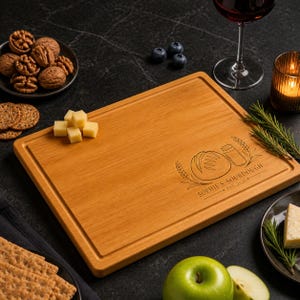 May include: A rectangular wooden cutting board with a juice groove, engraved with a loaf of bread, a jar, wheat stalks, and the text "SOPHIE'S SOURDOUGH EST. 2020". The board features a smooth, light brown wood grain finish and rounded corners.