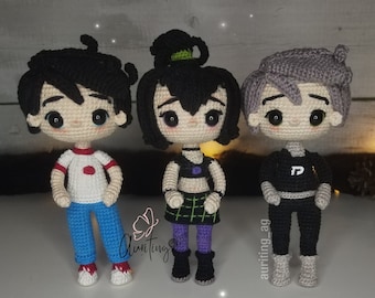 May include: Three handmade crochet dolls, each with unique outfits and hairstyles. The doll on the left wears a white shirt with red accents, blue pants, and red shoes. The middle doll has a black top, green and purple skirt, and black boots. The right doll is in a black outfit.
