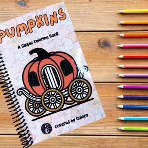 Może przedstawiać: Szkicownik ze spiralą z wizerunkiem dyni w kształcie powozu na okładce. Tytuł książki to "Pumpkins: A Simple Coloring Book", a na dole okładki widnieje napis "Covered by Colors".