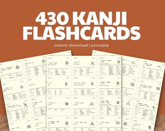 May include: Three flashcards with Japanese Kanji characters, featuring the text "430 Kanji Flashcards". The cards are cream-colored with black text and illustrations. The background is a warm, earthy tone, with the words "instant download | printable".
