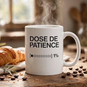 Peut inclure: Un mug blanc en céramique avec une anse, portant l'inscription noire DOSE DE PATIENCE et un graphique de barre de chargement indiquant 1%. De la vapeur s'échappe du mug posé sur une surface en bois à côté d'un croissant.