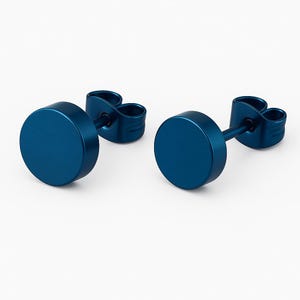 Könnte beinhalten: Zwei blaue runde Ohrstecker. Jeder Ohrring hat eine kreisförmige Vorderseite und einen Stecker mit Schmetterlingsverschluss. Die Ohrringe sind einfarbig, mattblau vor weißem Hintergrund.
