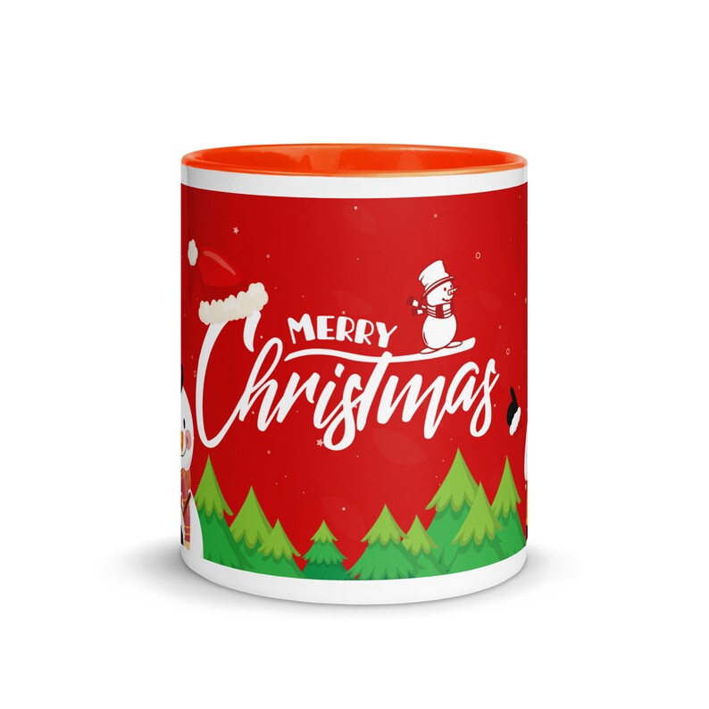 May include: A white ceramic mug with a red exterior and orange interior. The mug features a "Merry Christmas" design with snowmen, a Santa hat, and green Christmas trees. The design is set against a red background.