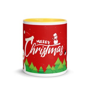 May include: A white ceramic mug with a yellow interior. The exterior features a red background with the words "Merry Christmas" in white script. Snowmen and Christmas trees decorate the mug.