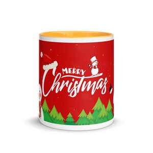 May include: A ceramic mug with a red background and the words "Merry Christmas" in white script. The mug features illustrations of snowmen, a Santa hat, and green Christmas trees. The interior of the mug is yellow.