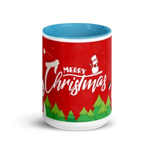 May include: A ceramic mug with a red exterior featuring a "Merry Christmas" design with snowmen and Christmas trees. The interior of the mug is light blue. A festive holiday-themed mug.