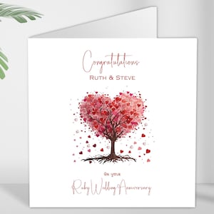 May include: A white card with a red heart-shaped tree made of smaller hearts. The text "Congratulations Ruth & Steve on your Ruby Wedding Anniversary" is printed on the card.