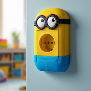 May include: A yellow and blue Minion-themed electrical outlet cover. The cover features the Minion's signature goggles and eyes above the outlet. The bottom portion is blue, and the outlet itself is yellow.