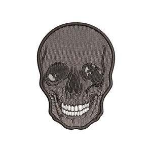 May include: Embroidered skull patch in shades of gray and black. The skull features detailed stitching, including eye sockets, a nose cavity, and a grinning mouth with white teeth. The patch has a dark gray outline.