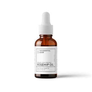 Puede incluir: Una botella de vidrio marrón de aceite de rosa mosqueta con un cuentagotas blanco. La etiqueta dice "THE ESSENTIAL HOUSE" y "ORGANIC COLD PRESSED ROSEHIP OIL". La botella contiene 30 ml de aceite.