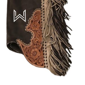 Puede incluir: Chaps de cuero marr&oacute;n con un dise&ntilde;o tallado y flecos. Los chaps tienen un logotipo "W" blanco en la parte delantera.