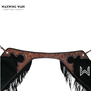 May include: Black leather chaps with brown tooled leather accents and fringe. The chaps feature a decorative floral pattern and the brand name "WAXWING WARI" at the top.
