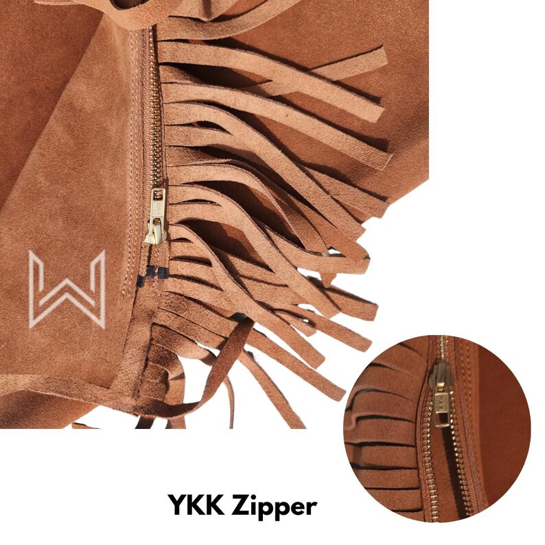 Pu&ograve; includere: Primo piano di un articolo in pelle scamosciata marrone con lunghe frange. Una cerniera YKK color oro corre verticalmente. Il testo "YKK Zipper" &egrave; visualizzato in basso. Un logo bianco &egrave; visibile sul lato sinistro.