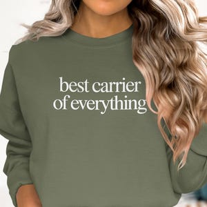 Olive green sweatshirt with "best carrier of everything" text.