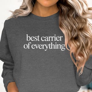 Dark gray crewneck sweatshirt with "best carrier of everything" text.