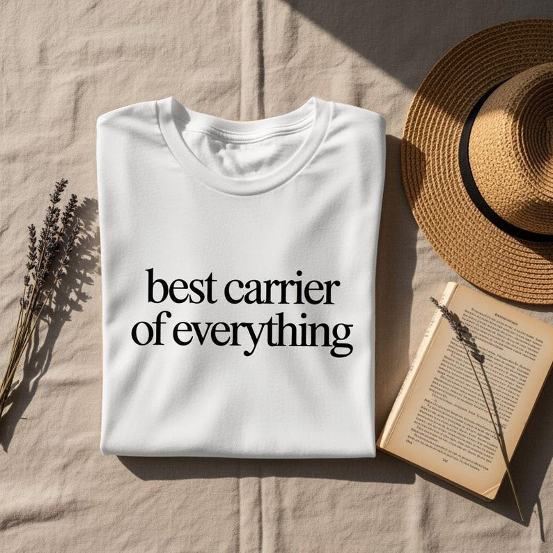 White t-shirt with "best carrier of everything" text, straw hat, and lavender.
