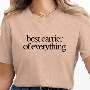 Peach t-shirt with "best carrier of everything" text in black.