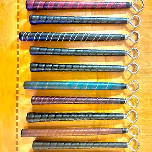 May include: A set of 12 golf club grips with different colored and patterned grips. Each grip has a metal loop at the end.