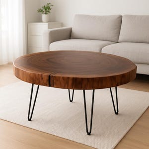 Könnte beinhalten: Ein runder, dunkelbrauner Couchtisch aus Holz mit schwarzen Haarnadelbeinen. Der Tisch hat eine natürliche Holzmaserung und steht auf einem hellen Teppich. Der Tisch hat einen Durchmesser von ca. 91 cm.