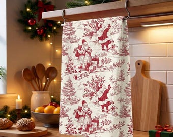 May include: A cream-colored kitchen towel featuring a repeating toile-style pattern in deep red ink. The design depicts Santa Claus figures carrying sacks of gifts, surrounded by evergreen trees and stacks of wrapped presents in a winter scene.